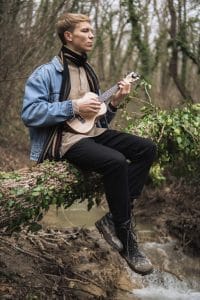 man sitting on a branch, playing guitar