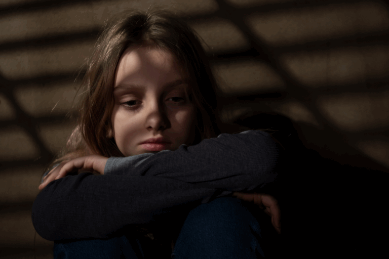 Sad girl sitting alone, showing signs of PTSD in children