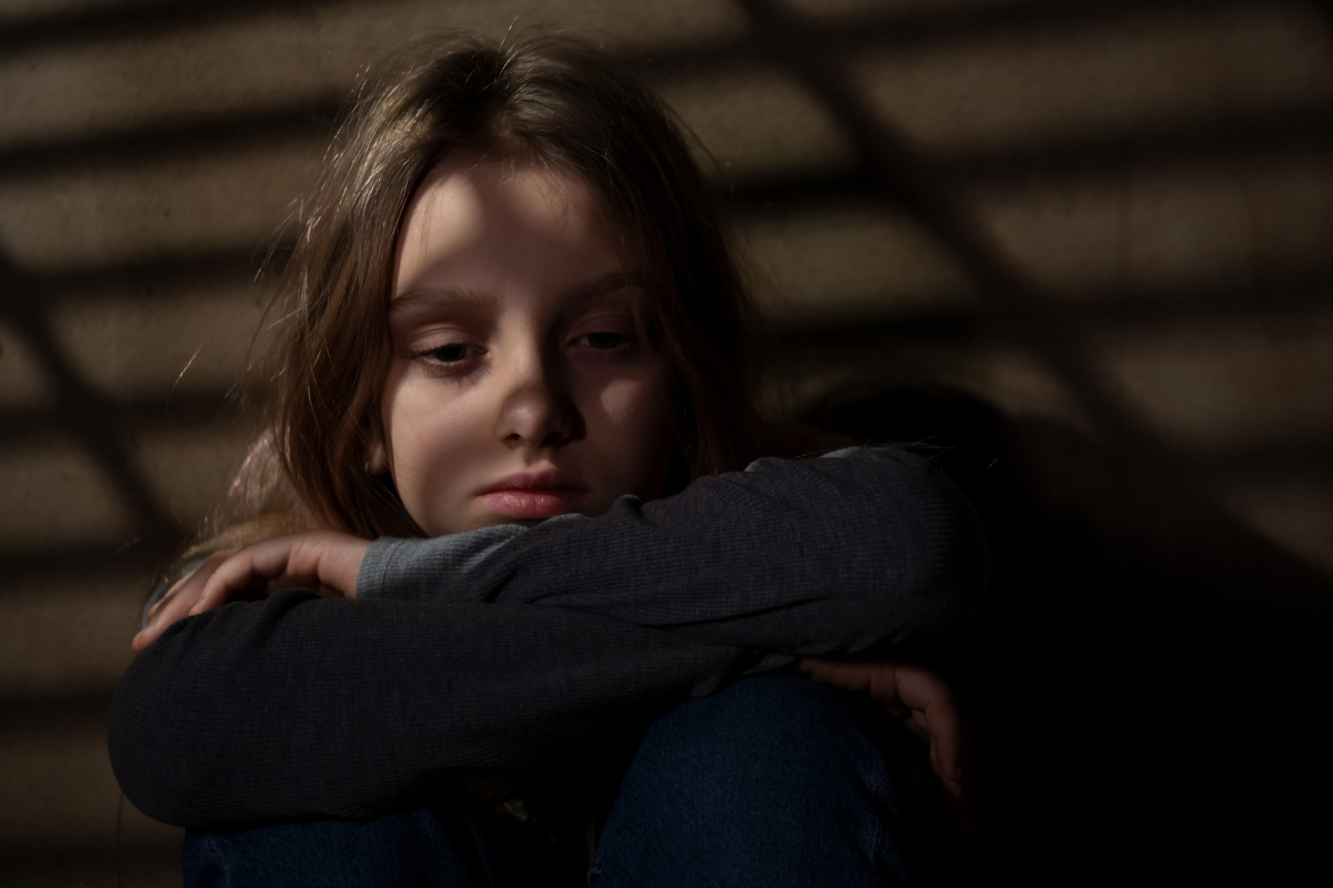 Sad girl sitting alone, showing signs of PTSD in children