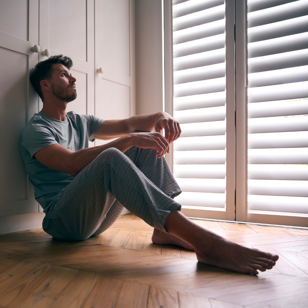 The Hidden Crisis of Male Loneliness and Depression 1 A man sitting alone indoors, showing signs of male loneliness and social isolation.