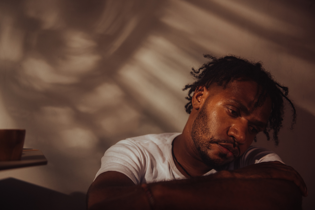 Man sitting alone looking overwhelmed, highlighting men’s mental health struggles.
