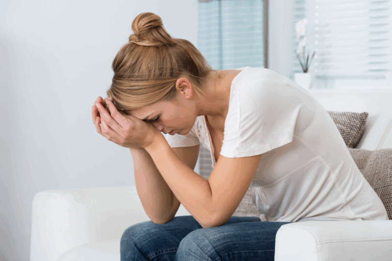 Woman sitting with head in hands, showing emotional distress linked to hormonal mood disorders like PMDD and PMS.