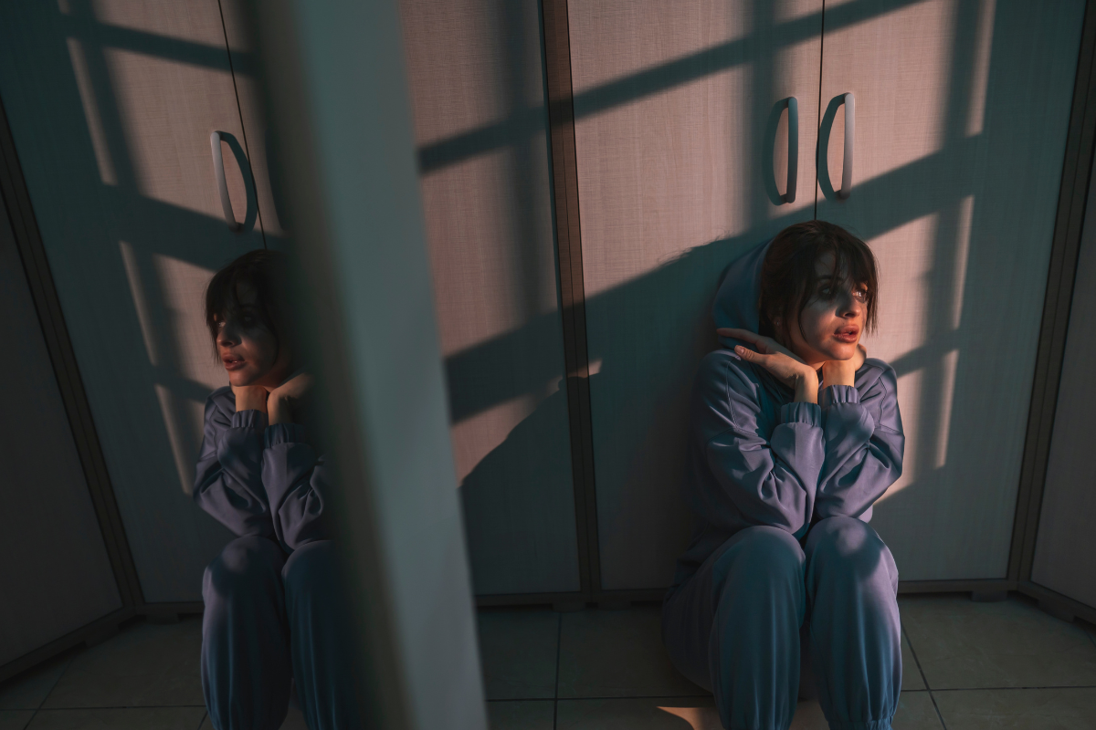 A woman sitting on the floor looking distressed, illustrating the emotional weight of living with an anxiety disorder.