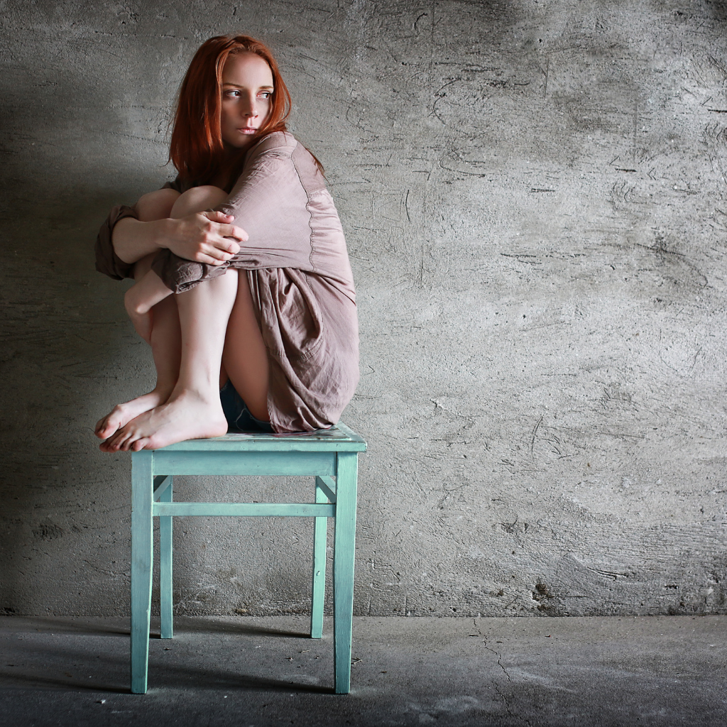 What Is Complex PTSD (CPTSD)? Understanding Symptoms, Differences, and Treatment 1 Woman sitting alone on a chair, hugging her knees, symbolizing the emotional impact of prolonged trauma in CPTSD.