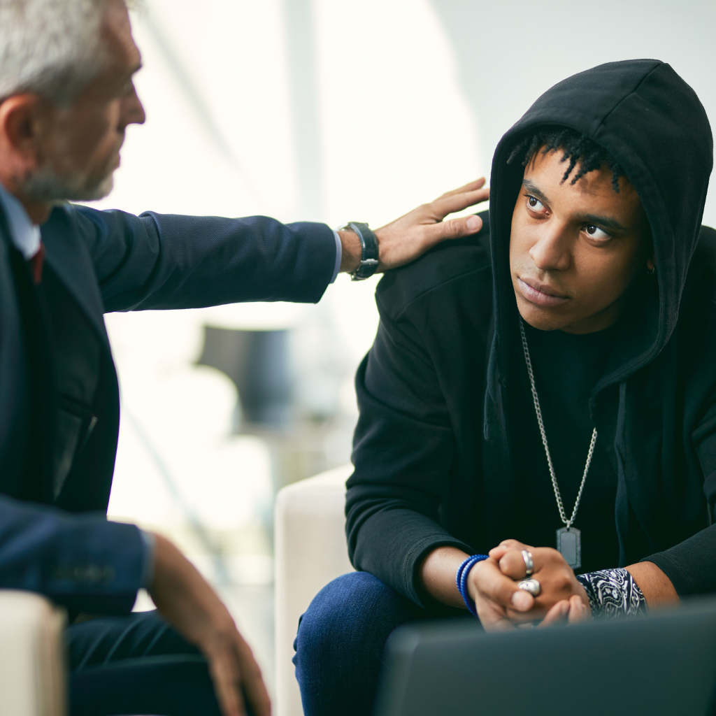 Exploring the Intersection of Masculinity and Men's Mental Health 1 Young man in a hoodie receiving support during a serious conversation.