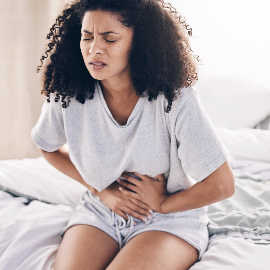 Woman holding her stomach, showing discomfort from PMS symptoms.