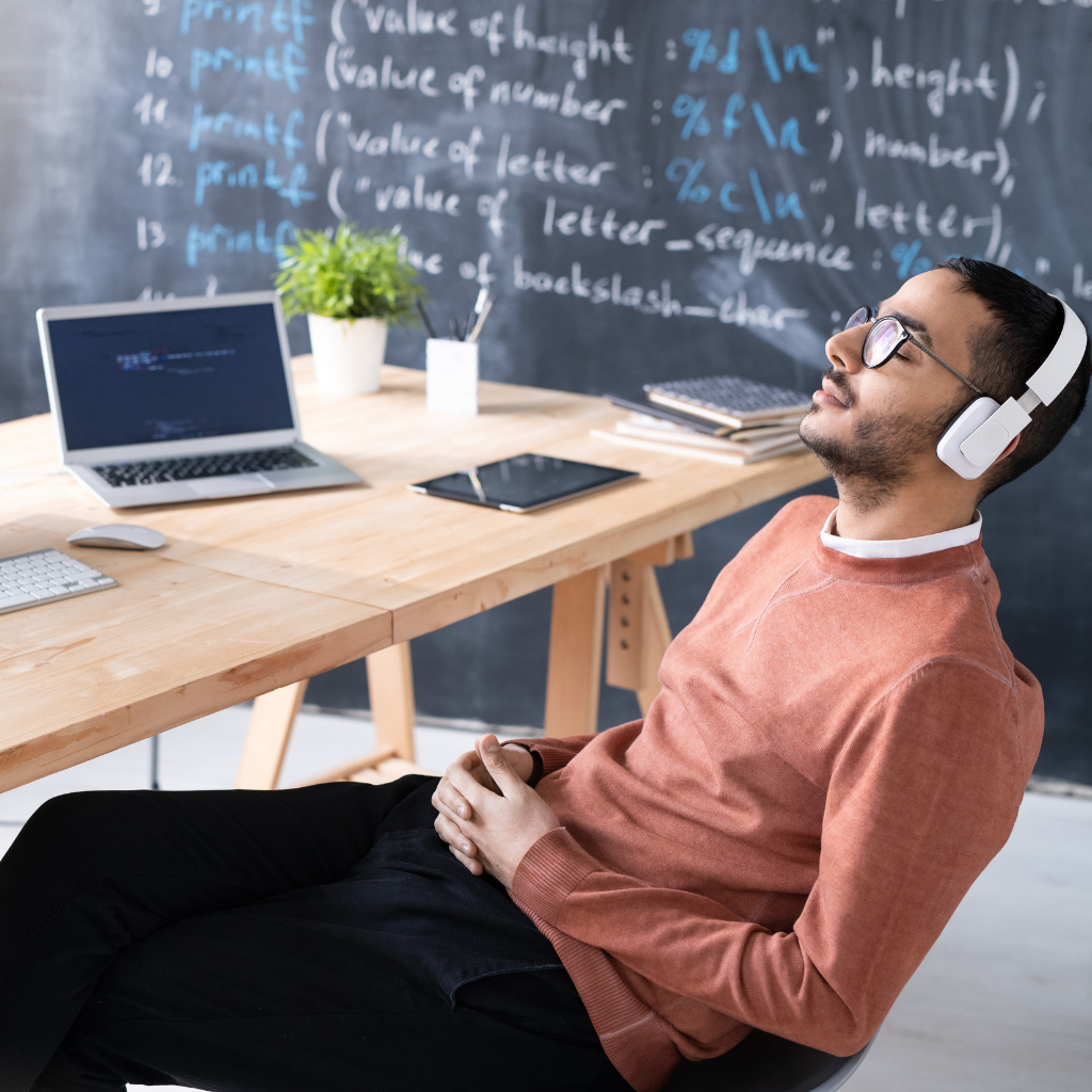 Man resting at his desk with headphones on, taking a break to manage ADHD burnout.
