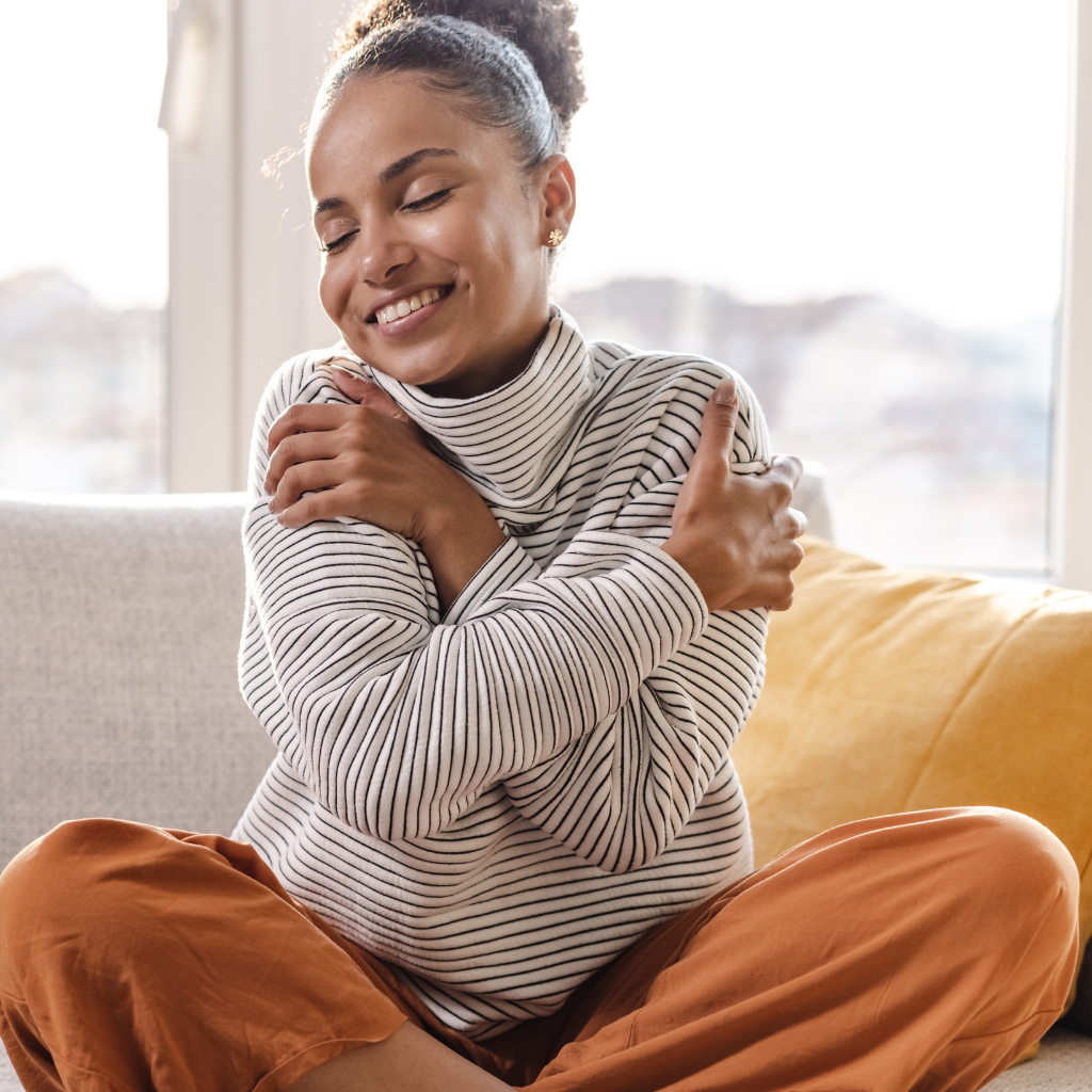 How Self-Esteem Shapes Mental Health: What You Need to Know 2 Smiling woman hugging herself, showing self-compassion and self-acceptance.