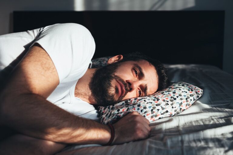 Man lying in bed looking withdrawn, reflecting the quiet struggle of depression in men.