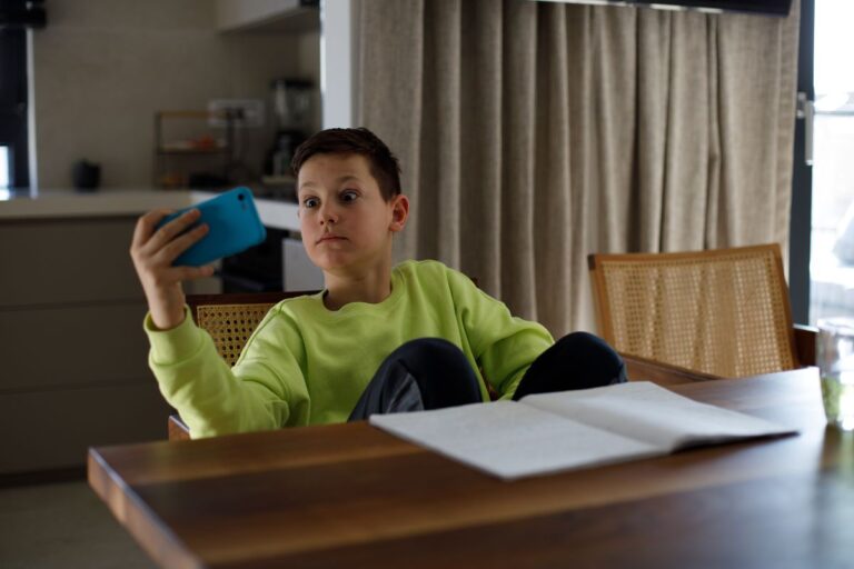Child getting distracted by a phone while trying to do homework, showing signs of ADHD in children.