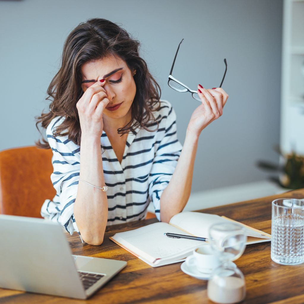Woman feeling overwhelmed at her desk, showing signs of stress that can lead to anger issues.