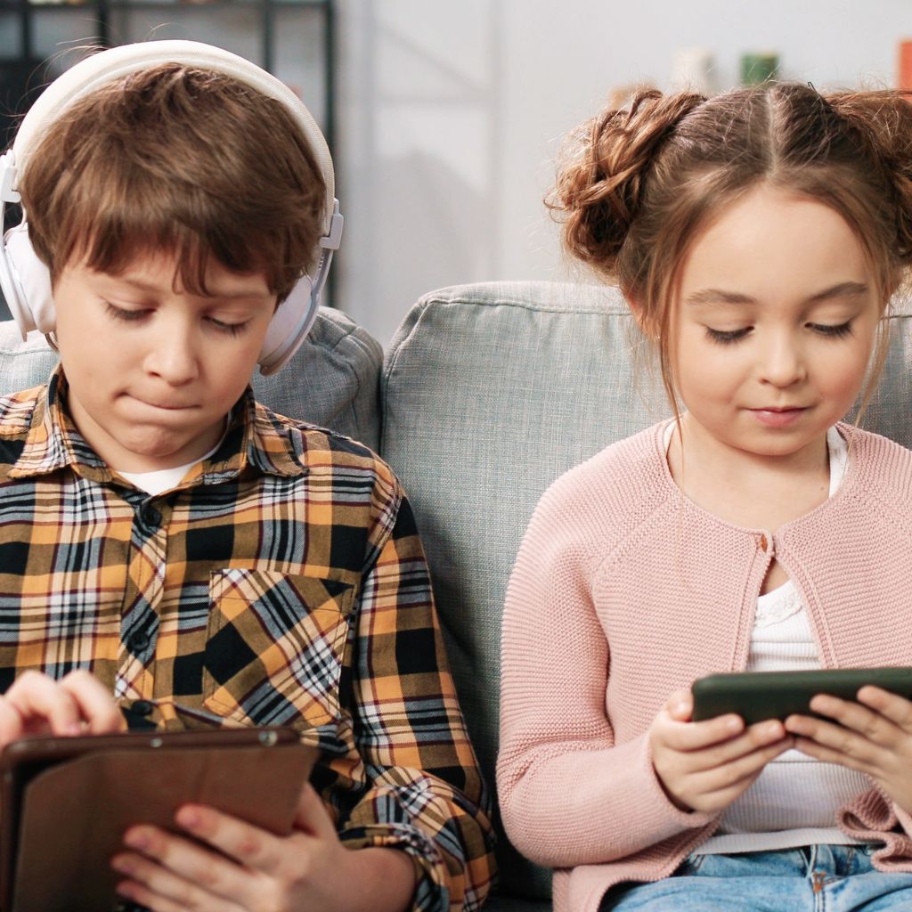 Children using tablets and headphones, illustrating how heavy digital media use may contribute to ADHD symptoms in children.