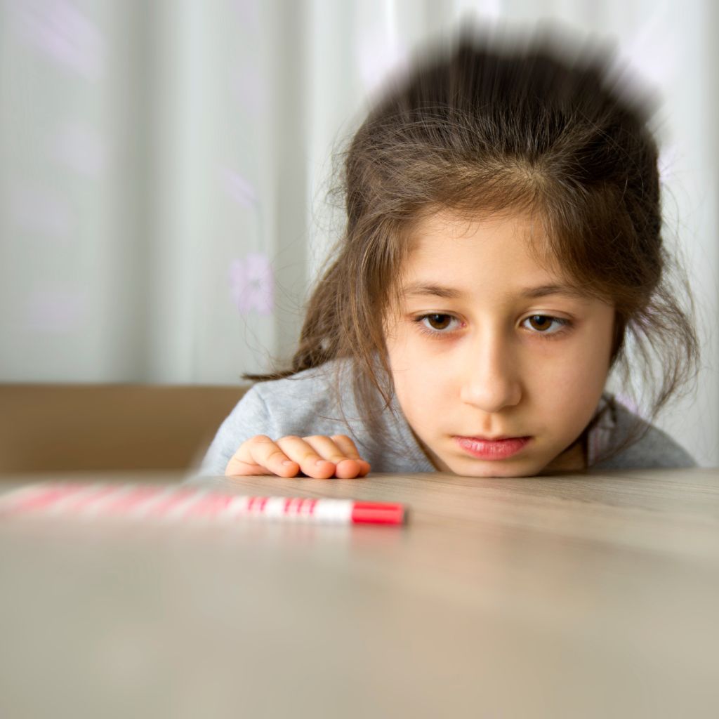 Young girl fixated on a pen, illustrating obsessive focus—a common sign of OCD in children.