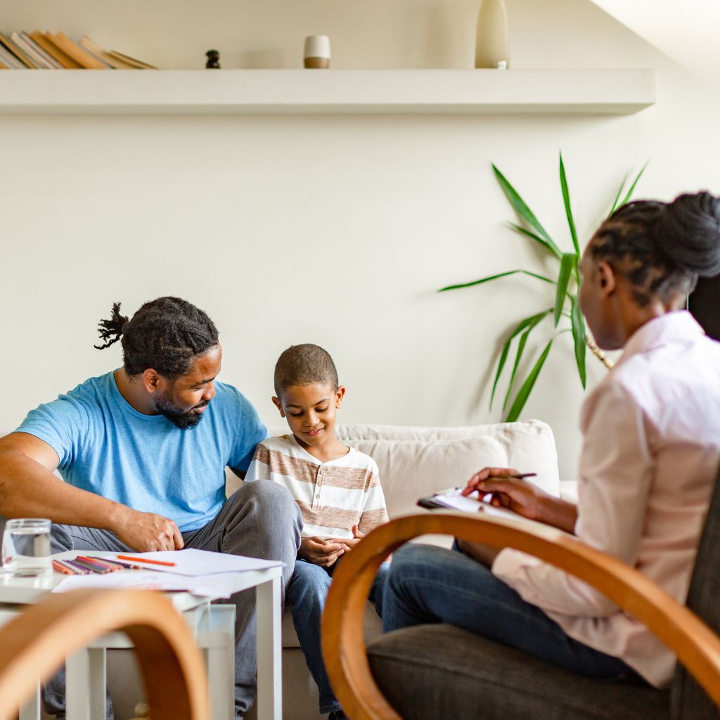 Child in therapy session with parent and counselor, highlighting family support in OCD treatment for children.