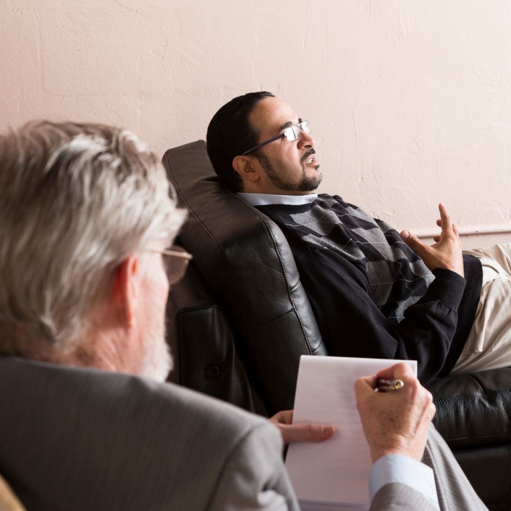 Understanding the Bipolar Spectrum: The Brain’s Role in Mood Swings and Mania 2 Man talking with a therapist, highlighting the role of treatment and support in managing bipolar disorder.