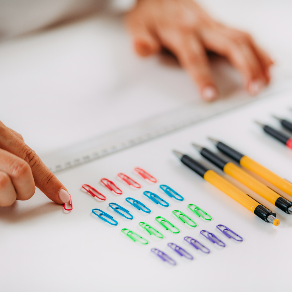 Person carefully arranging paper clips by color and size, showing compulsive OCD behavior.
