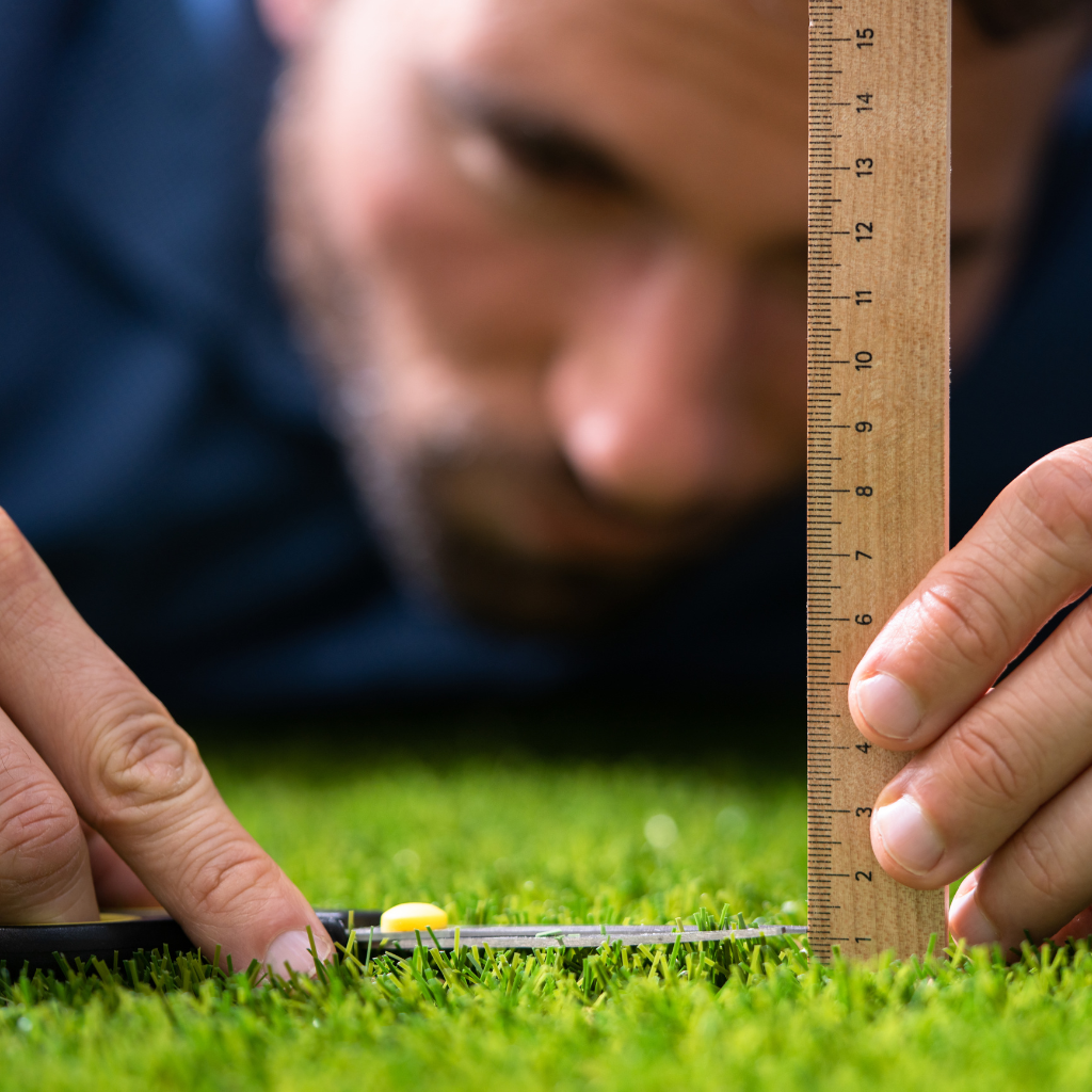 Man measuring grass with a ruler and trimming it precisely, illustrating obsessive OCD rituals