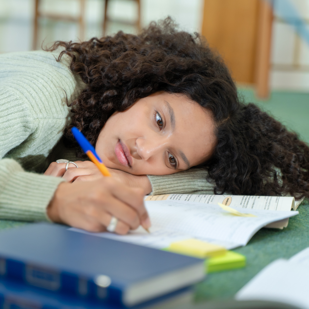 Woman lying on the floor, having a hard time focusing on her work, a common struggle with ADHD and procrastination.