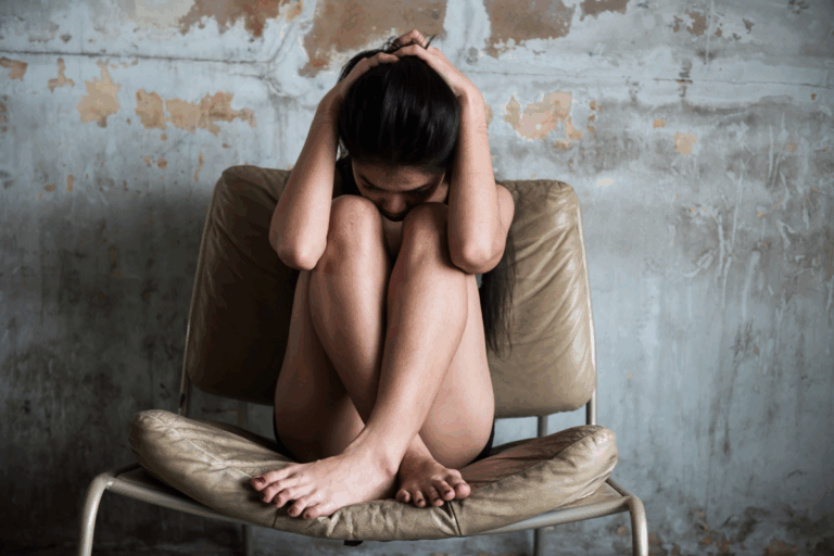 Distressed woman sitting curled up in a chair, showing the emotional toll of trauma