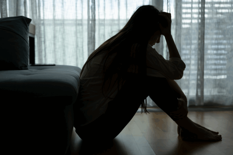 Silhouette of a distressed woman sitting on the floor, showing the emotional struggles DBT can help manage.