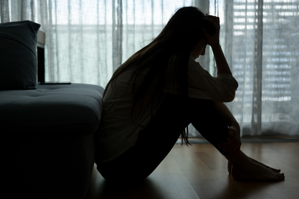 Silhouette of a distressed woman sitting on the floor, showing the emotional struggles DBT can help manage.
