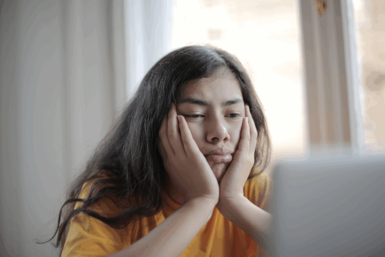 Young woman staring at a screen with a sad, tired expression—illustrating emotional fatigue and symptoms of a mood disorder