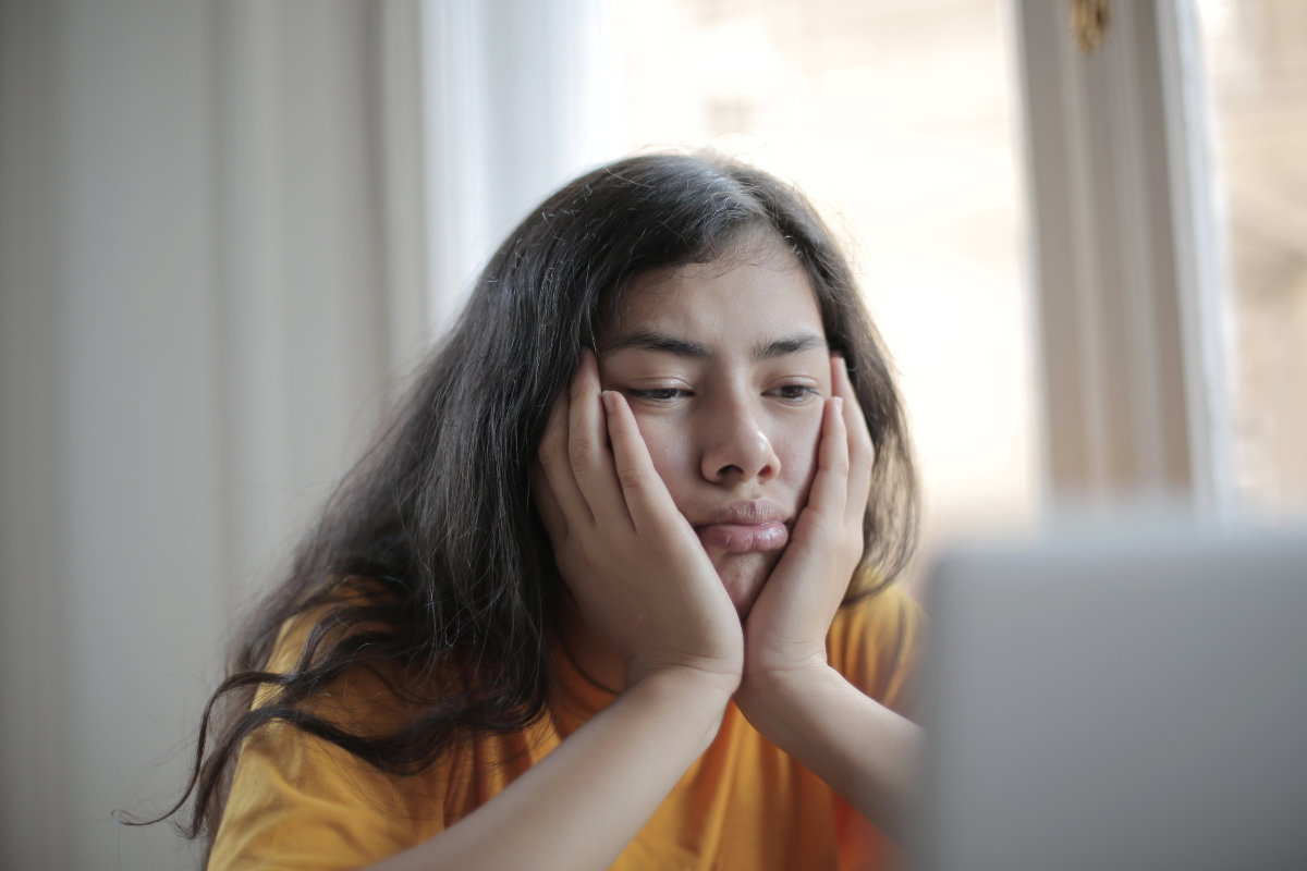 Young woman staring at a screen with a sad, tired expression—illustrating emotional fatigue and symptoms of a mood disorder