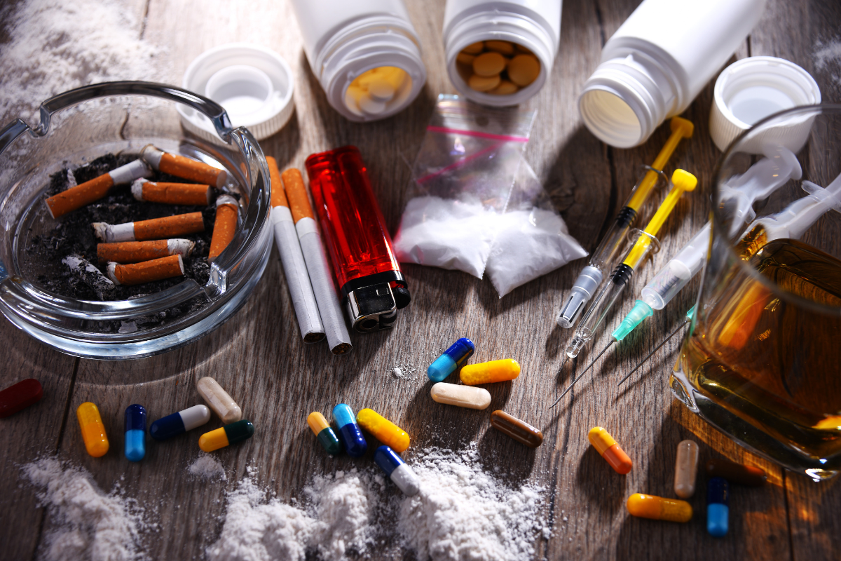Drugs, pills, alcohol, and syringes symbolizing substance use disorder.