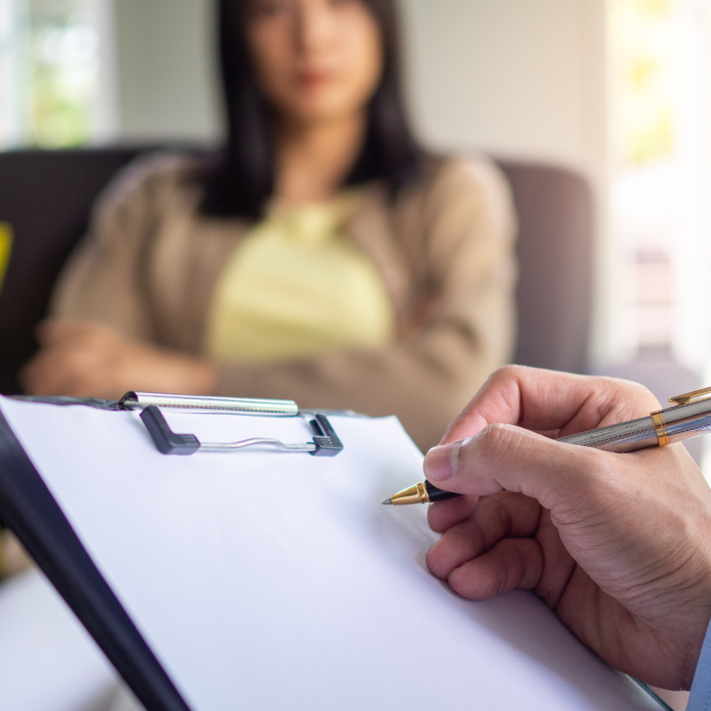 Therapist taking notes during a session with a new mother discussing postpartum treatment options.