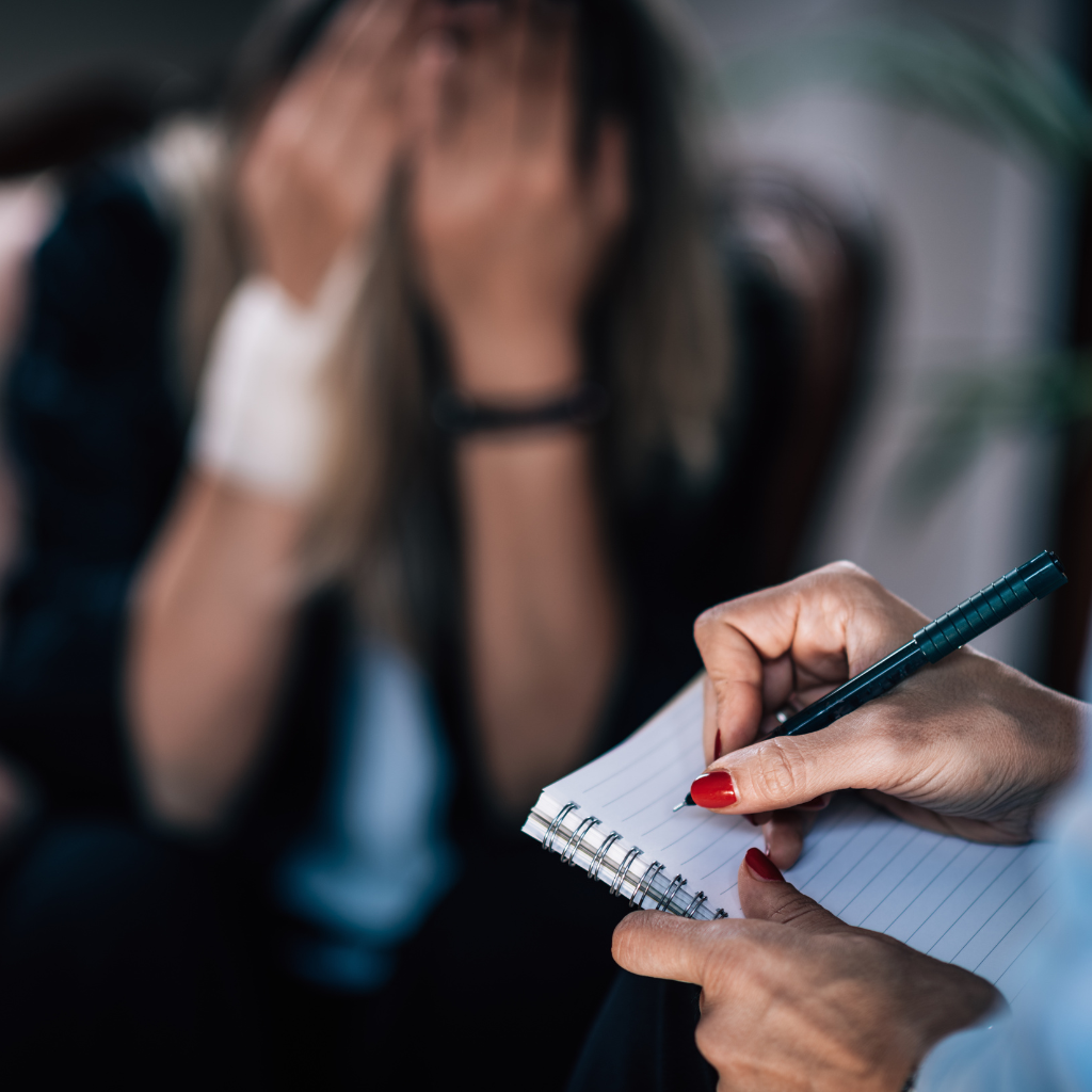 What Is Dialectical Behavior Therapy (DBT) and How It Helps in Managing Mental Health 1 Therapist taking notes during a session with a distressed patient, illustrating the supportive and structured nature of DBT.