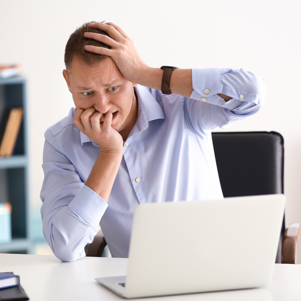 A man looking at his laptop, anxious and worried