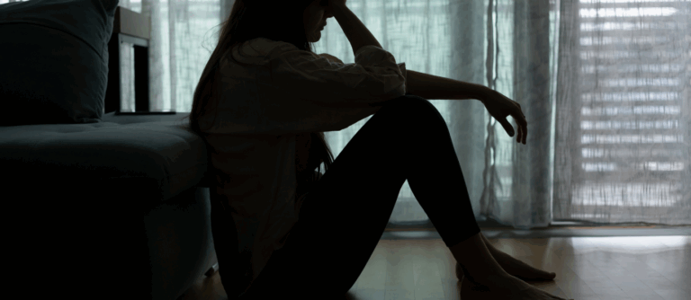 Woman sitting on the floor in shadow showing depression