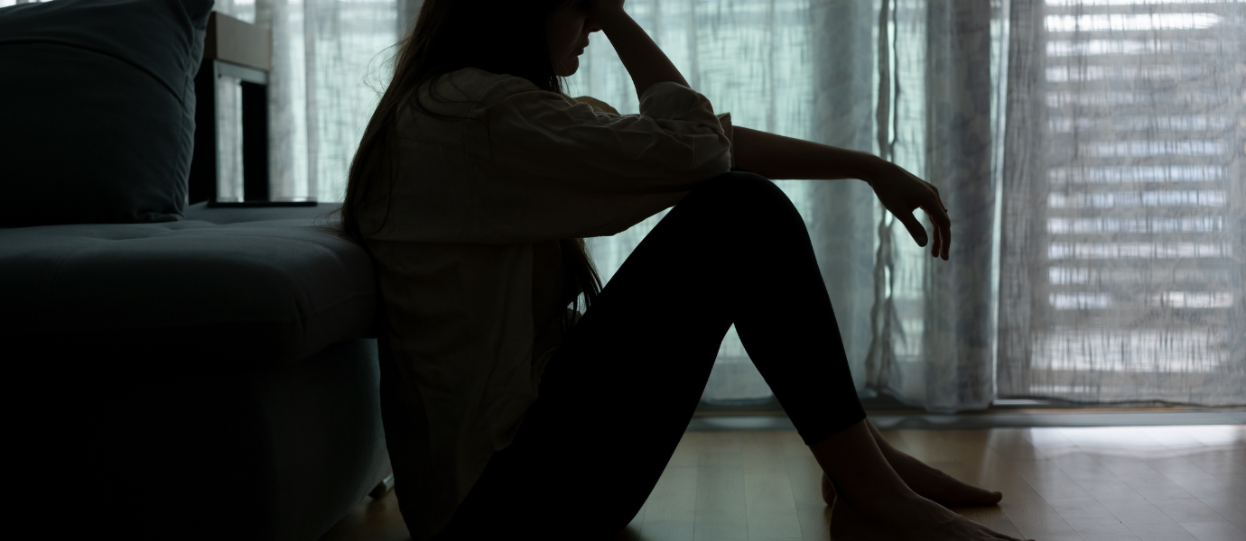 Woman sitting on the floor in shadow showing depression