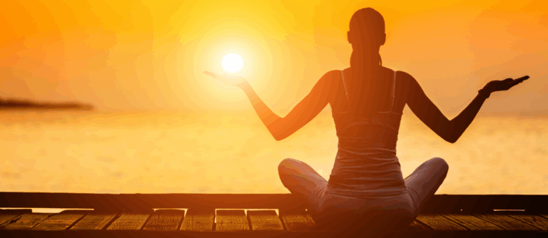 Person practicing mindfulness meditation at sunrise by the water.
