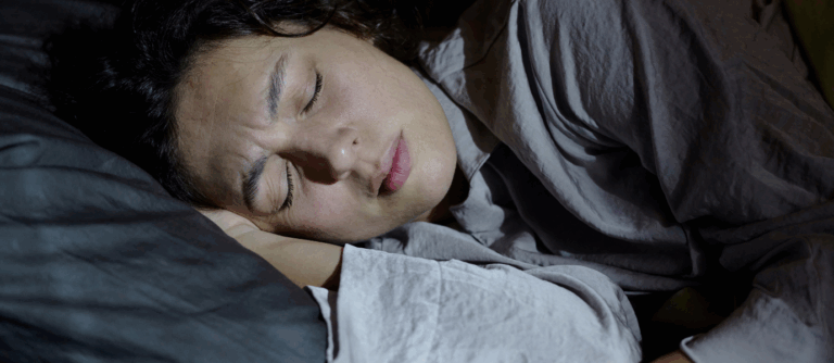 Person experiencing restless sleep linked to REM Sleep Behavior Disorder.