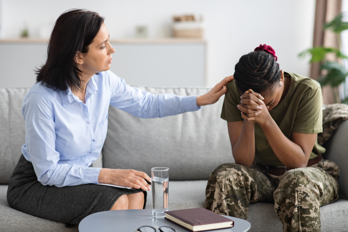 Therapist comforting a distressed female veteran with PTSD.