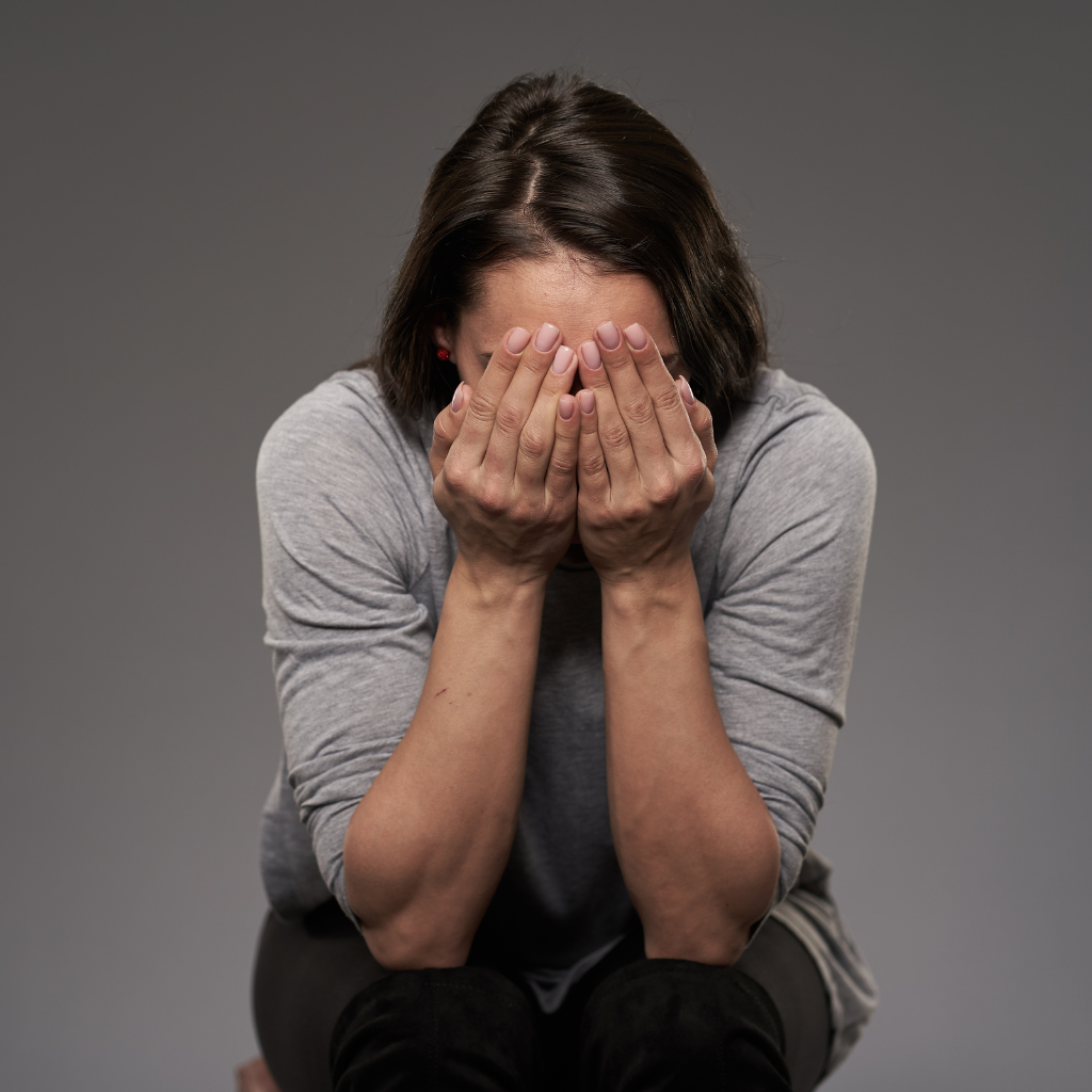 Woman covering her face in distress, representing the emotional pain of rejection sensitive dysphoria in ADHD