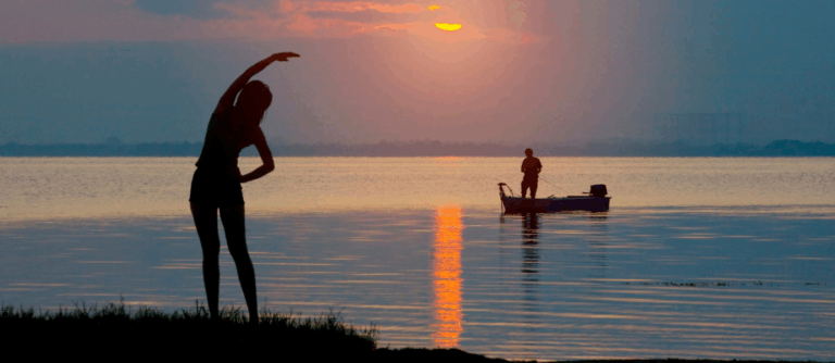 Person stretching by the water at sunrise, symbolizing wellness after TMS.