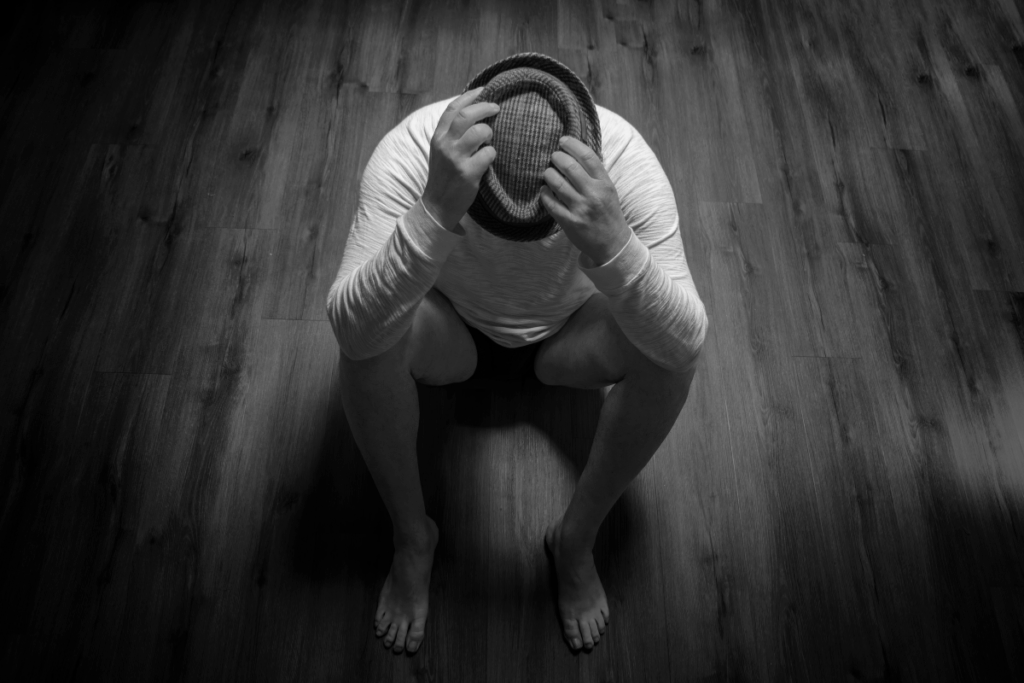 Generalized Anxiety Disorder vs. Major Depressive Disorder: Symptoms, Differences, and Treatment Strategies 2 Person sitting on the floor with head down, showing signs of depression and anxiety