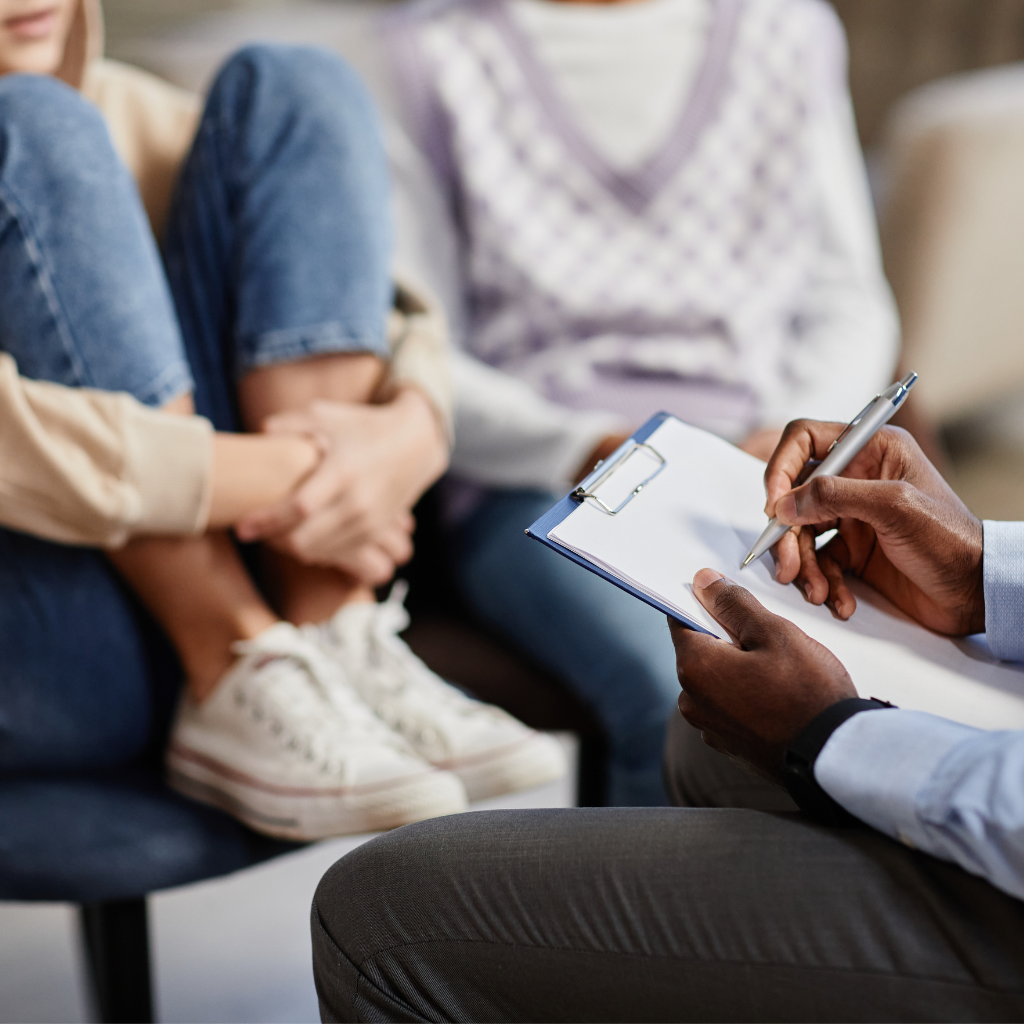 Therapist taking notes during a CBT for children session with young patients.