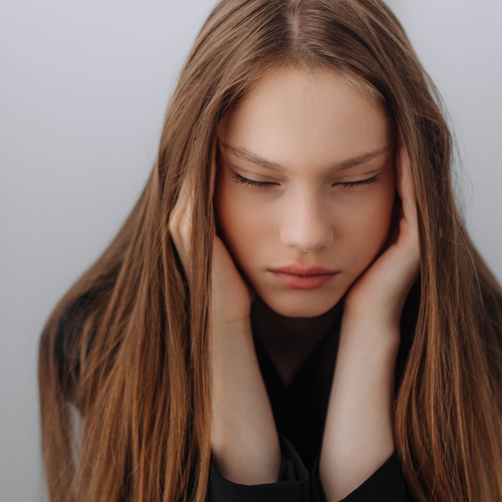 Generalized Anxiety Disorder vs. Major Depressive Disorder: Symptoms, Differences, and Treatment Strategies 1 Woman sitting with eyes closed, appearing anxious or tense.