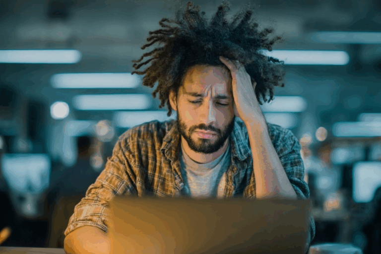 Man sitting at desk, drained and stressed, showing clear signs of burnout at work
