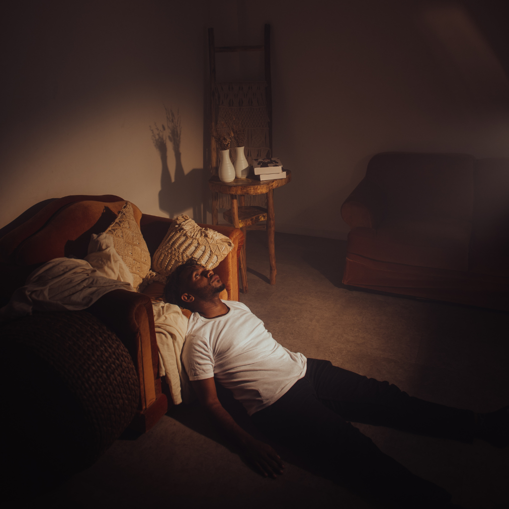 Person resting against a couch, struggling with emotional pain