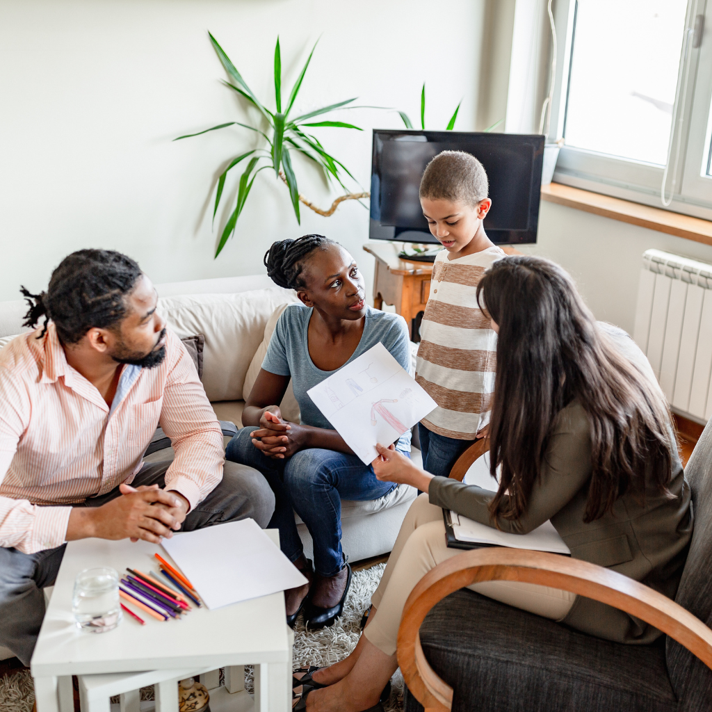 How Panic Attacks In Children Can Obstruct Their Mental Growth — Symptoms, Impacts, And What Helps 2 Parents and a child talking with a professional about school support and coping strategies for anxiety or panic.