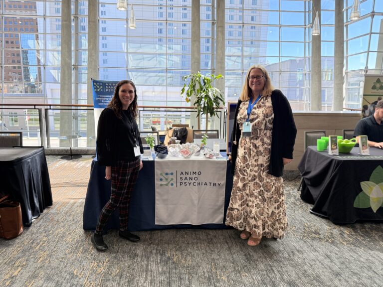 Two women standing at the Animo Sano Psychiatry booth during the CFHA Conference.