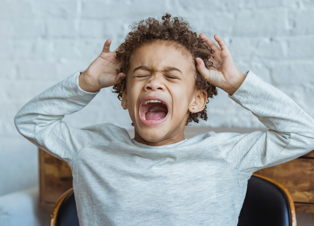 Child yelling with hands on their head, illustrating impulsive outbursts linked to impulse control difficulties.