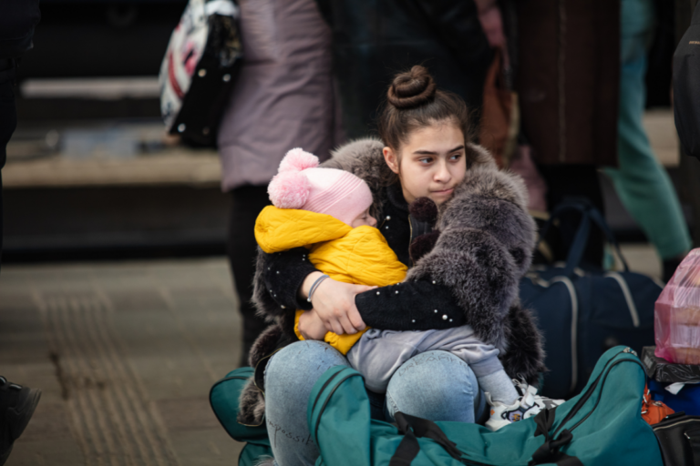 Animo Sano Psychiatry 41 A woman holding a baby while sitting with luggage, reflecting the emotional stress and uncertainty often experienced during immigration.