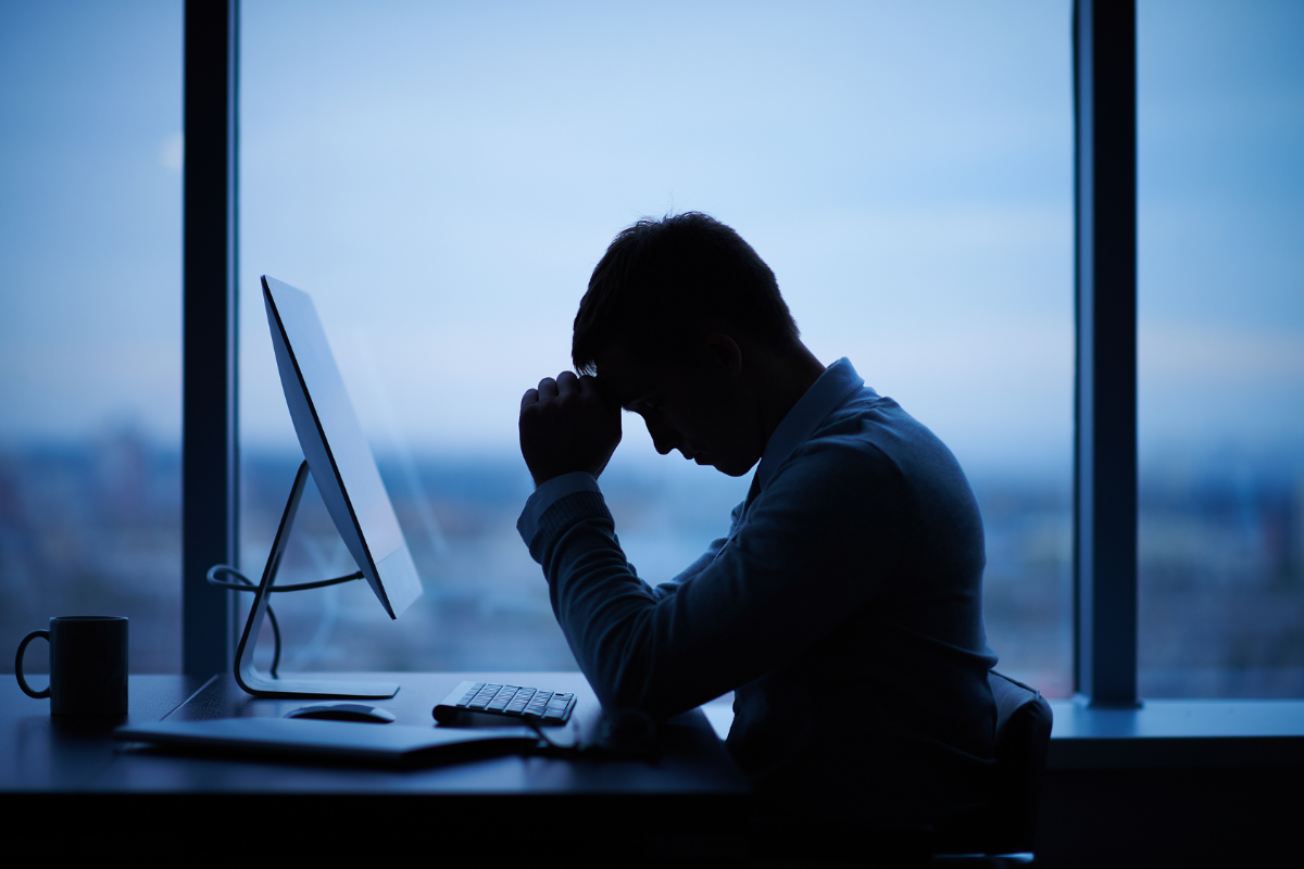 A person at a desk with their head down, showing the quiet emotional weight of high functioning depression.