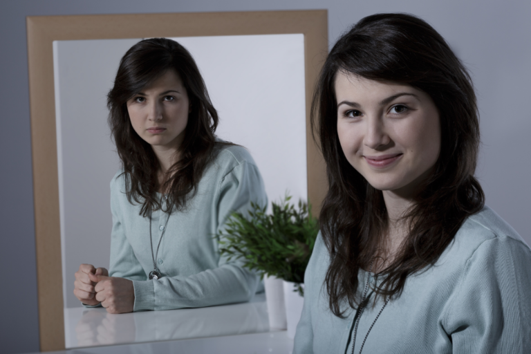 Woman facing her reflection, showing two contrasting mood states associated with bipolar disorder