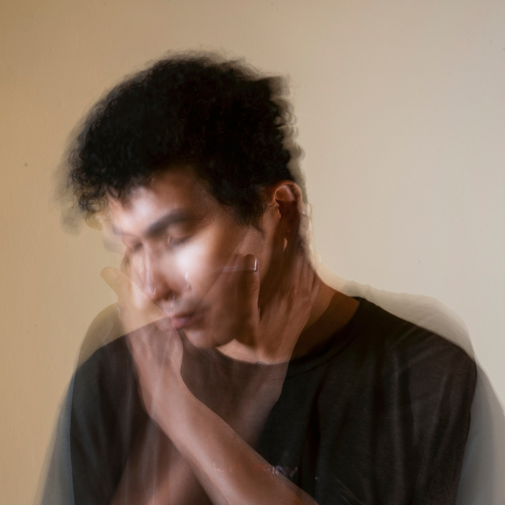 Blurred image of a man holding his face, showing stress and overwhelm.